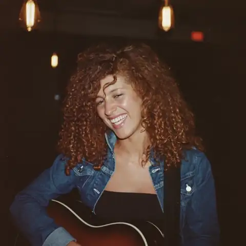Saffi, a singer-songwriter, laughing backstage with her guitar